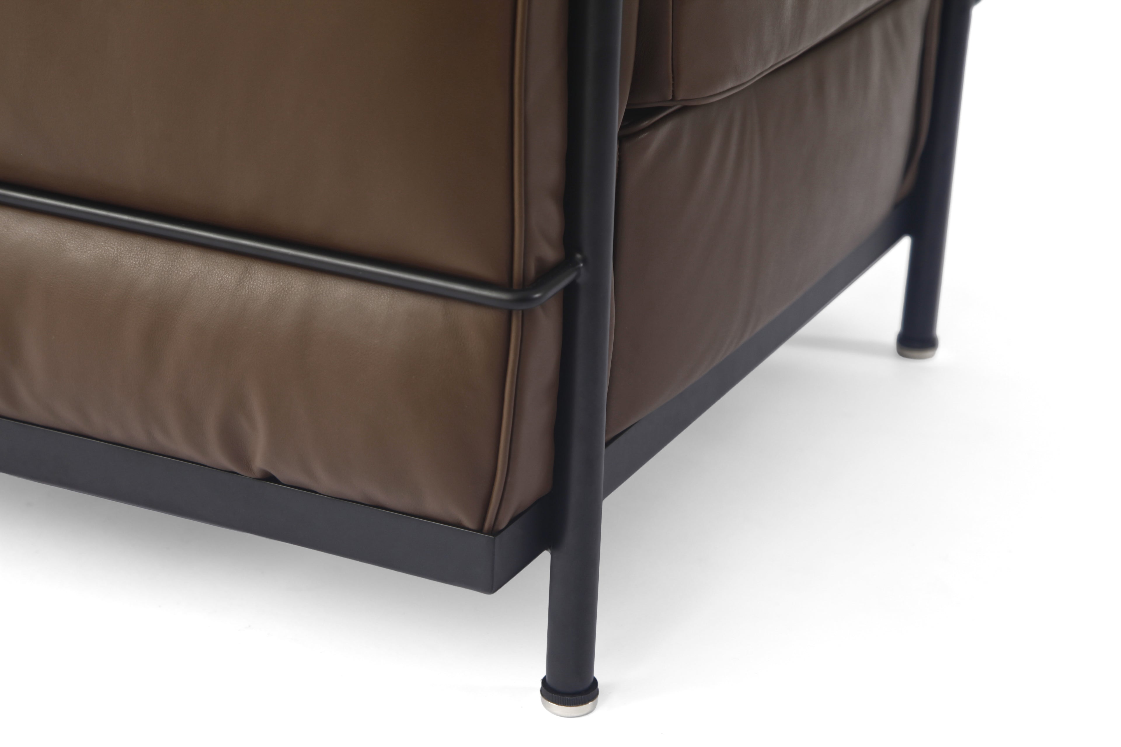 Close-up of a brown LC2 leather chair corner with a black metal frame and legs on a white background.
