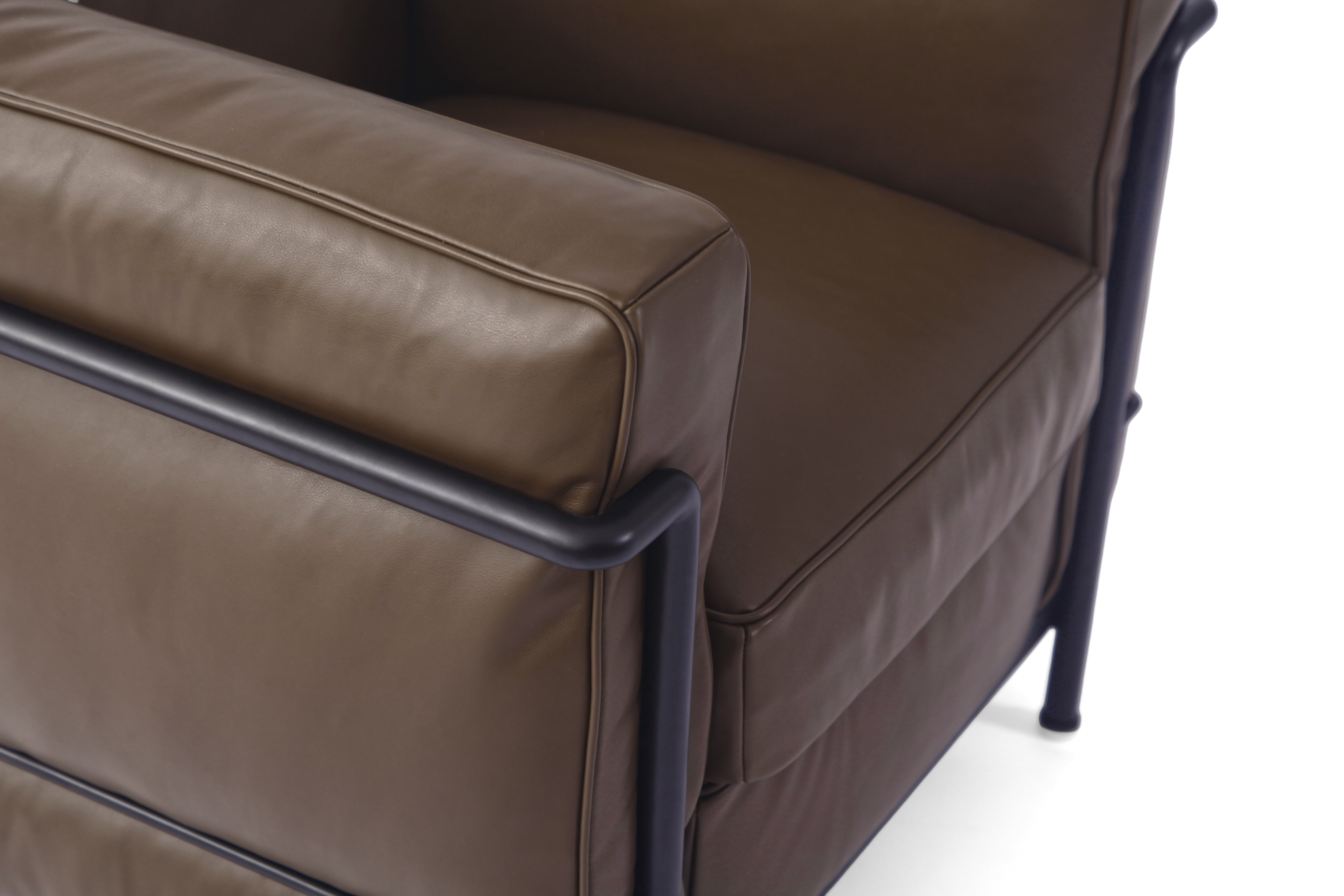Close-up of a brown leather LC2 armchair with a black metal frame, showing the seat cushion, backrest, and armrest detail against a white background.