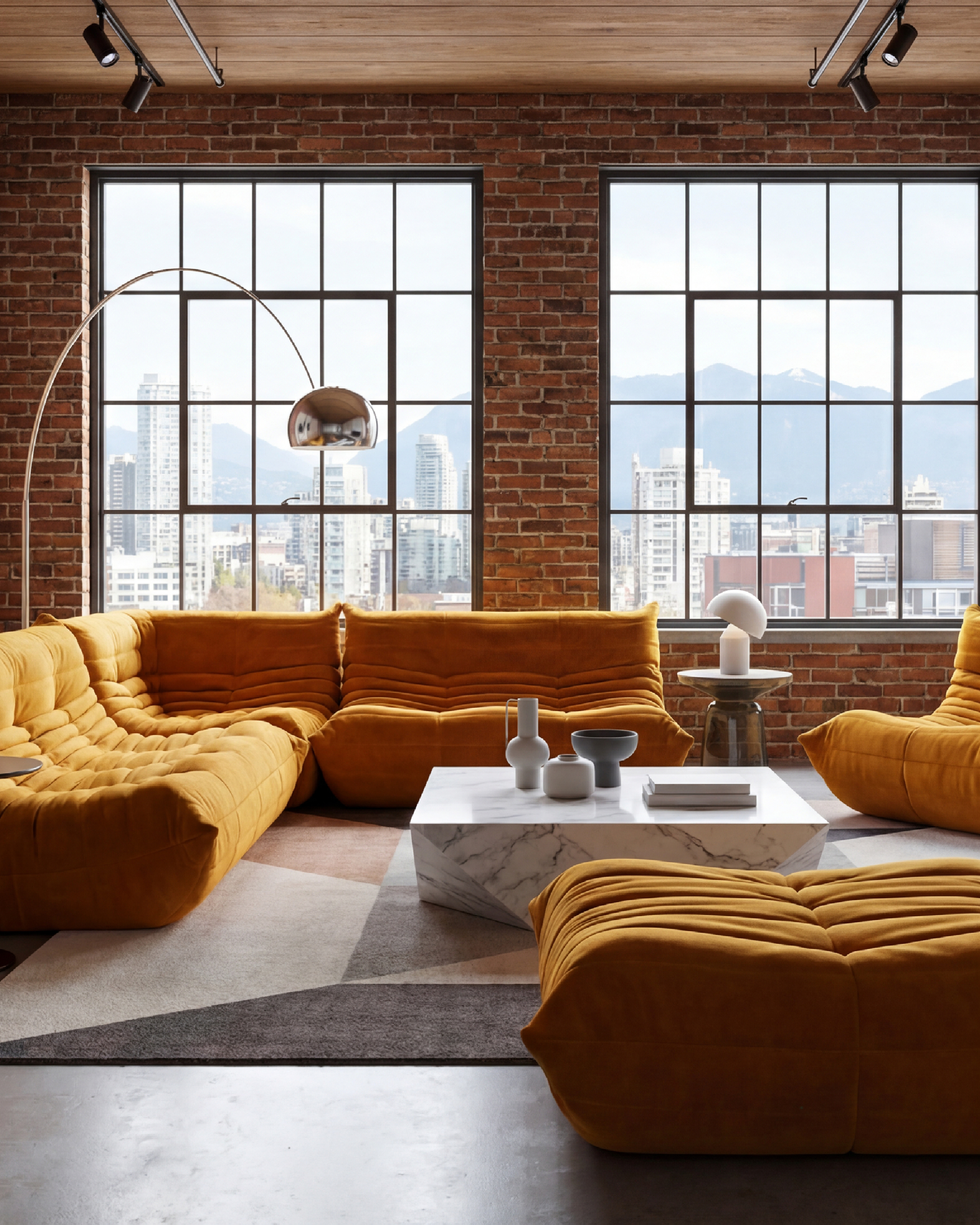 Modern living room with yellow Michel Ducaroy TOGO sectional sofa reproduction, marble coffee table, and large windows with cityscape view in the USA in Canada
